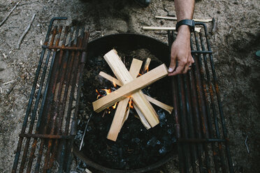 High angle view of man burning firewood in fire pit at campsite - CAVF37579