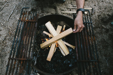 Hoher Blickwinkel auf einen Mann, der Brennholz in einer Feuerstelle auf einem Campingplatz verbrennt - CAVF37579