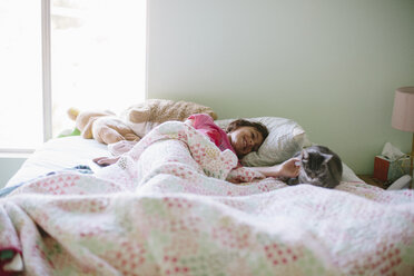 Girl petting cat while lying on bed - CAVF37596