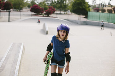 Mädchen trägt Skateboard beim Spaziergang im Park - CAVF37604