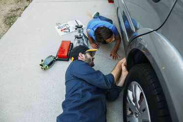 High angle view of father teaching son to repair car at driveway - CAVF37614