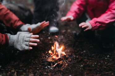 Ausgeschnittenes Bild von Mutter und Tochter, die sich am Lagerfeuer die Hände wärmen - CAVF37628