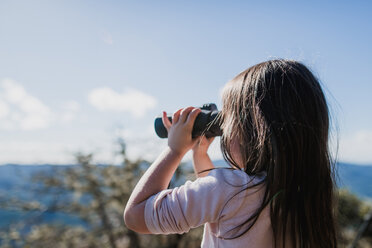 Girl looking through binoculars against sky - CAVF37631