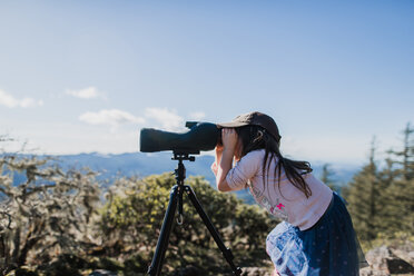 Seitenansicht eines Mädchens, das durch ein Teleskop schaut, während es gegen den Himmel steht - CAVF37632