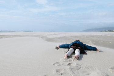 Girl lying on sand at beach against sky - CAVF37640