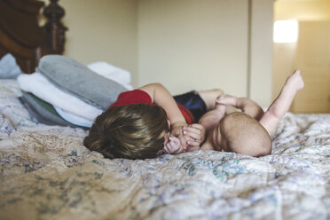 Bruder spielt mit einem kleinen Jungen, während er zu Hause auf dem Bett liegt - CAVF37695