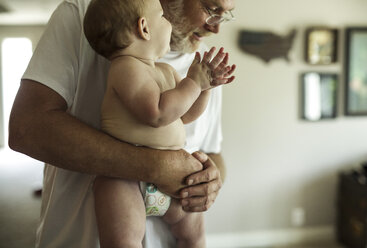 Großvater trägt seinen Enkel ohne Hemd im Stehen nach Hause - CAVF37711