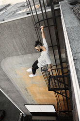 High angle view of man sitting on ladder against building - CAVF37723