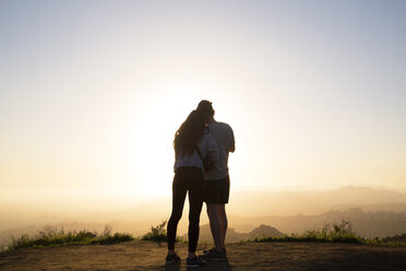 Rear view of couple standing on mountain against clear sky during sunset - CAVF37808