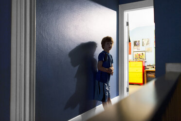 Portrait of boy standing against blue wall at home - CAVF37826