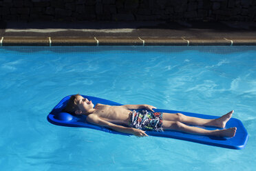 High angle view of boy relaxing on inflatable raft in swimming pool - CAVF37827