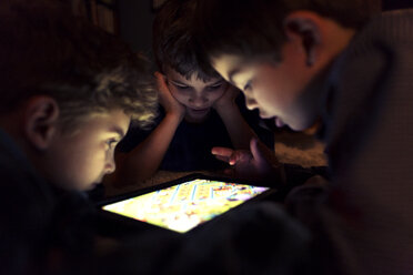 Siblings playing game on tablet computer at home - CAVF37835