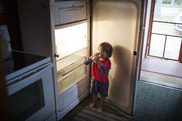 Junge trinkt Dosengetränk aus dem Kühlschrank - CAVF37857