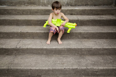 Junge mit Wasserpistole auf der Treppe sitzend - CAVF37886