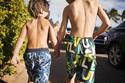 Two boys walking along cars stock photo