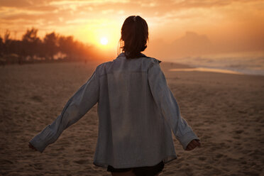 Junge Frau betrachtet den Sonnenuntergang am Strand - CAVF37926