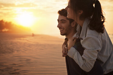 Man giving piggyback ride to his girlfriend on beach - CAVF37928