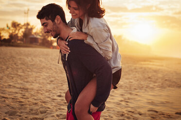 Mann nimmt seine Freundin am Strand huckepack - CAVF37929