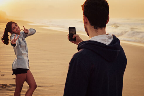 Mann fotografiert seine Freundin am Strand - CAVF37930