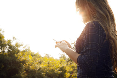 Teenage girl texting at sunset - CAVF37948