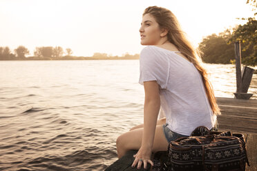 Teenager-Mädchen entspannt sich am Pier bei Sonnenuntergang - CAVF37949