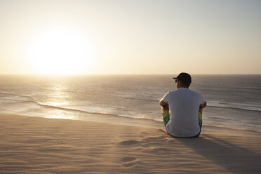 Mann sitzt am Strand - CAVF37955