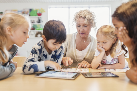 Oberlehrer und Kinder mit Tabellen und digitalen Tablets, lizenzfreies Stockfoto