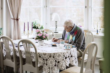 Älterer Mann schreibt in ein Buch am Esstisch eines Pflegeheims - MASF03260