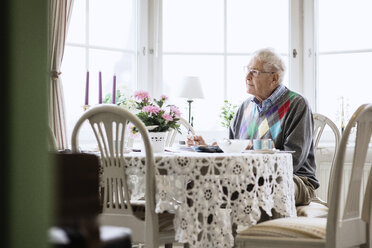 Nachdenklicher älterer Mann sitzt am Esstisch im Pflegeheim - MASF03261