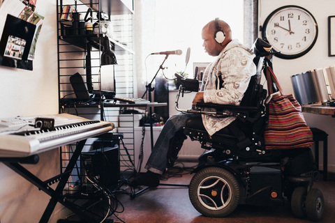 Seitenansicht eines behinderten Musikers mit Kopfhörern im Aufnahmestudio, lizenzfreies Stockfoto