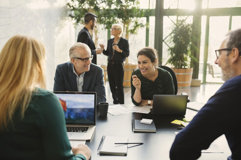 Lächelnde Geschäftsfrau, die mit Kollegen in einem kreativen Büro diskutiert - MASF03281