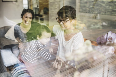 Smiling family enjoying music seen through glass window - MASF03290