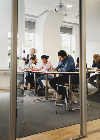 Teacher teaching students in language class seen through open door stock photo