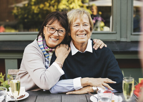 Lächelnde ältere Freundinnen mit Arm um am Cafétisch - MASF03309