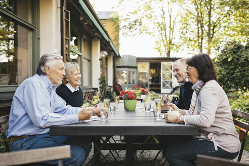 Seitenansicht eines glücklichen älteren Paares, das in einem Restaurant im Freien isst - MASF03311