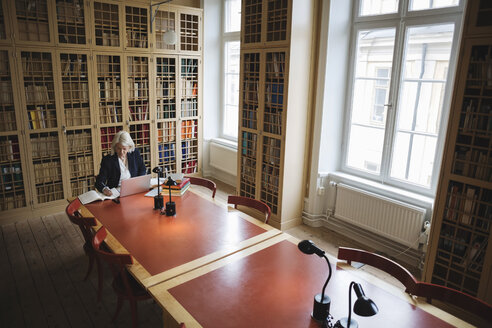 Ältere Frau recherchiert am Tisch in der juristischen Bibliothek - MASF03338