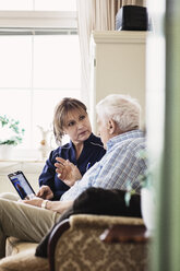 Älterer Mann im Gespräch mit dem Pfleger, während er ein digitales Tablet im Pflegeheim benutzt - MASF03350