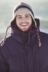 Porträt eines glücklichen jungen Mannes, der im Winter im Freien steht - MASF03360
