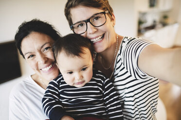 Porträt eines lächelnden lesbischen Paares mit Kleinkind zu Hause - MASF03379