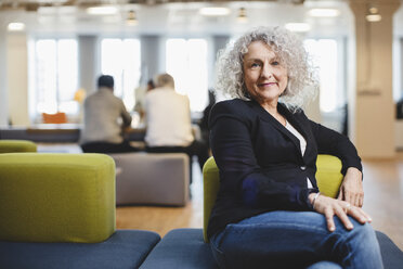 Portrait of senior woman sitting on couch at corridor - MASF03390