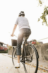 Rückansicht einer Radfahrerin auf der Straße bei klarem Himmel - MASF03418