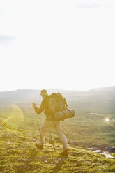 Rear view of man hiking on mountain against sky during sunny day - MASF03434