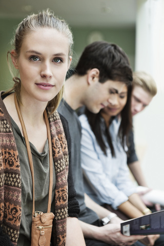 Porträt einer schönen jungen Frau mit Freunden im Hintergrund, lizenzfreies Stockfoto