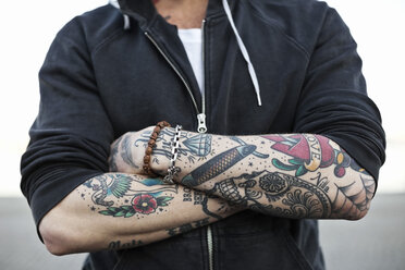 Midsection of a tattooed man with arms crossed - MASF03461