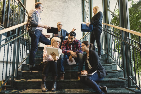 Multi-ethnische Geschäftsleute diskutieren auf der Treppe in einem kreativen Büro - MASF03466