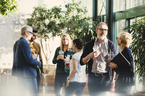 Multi-ethnic business people discussing while having juice in office - MASF03471