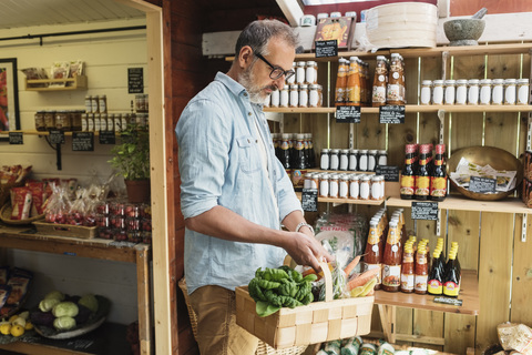 Älterer Mann trägt Korb beim Einkaufen im Lebensmittelgeschäft, lizenzfreies Stockfoto