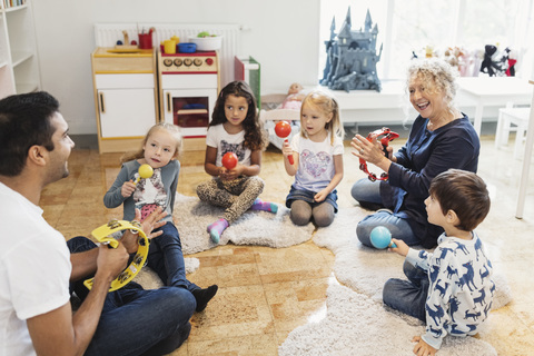 Glückliche Lehrer und Kinder mit Musikinstrumenten im Klassenzimmer, lizenzfreies Stockfoto