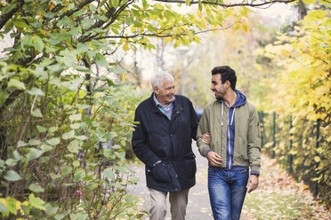 Happy senior man with caretaker walking in park - MASF03520