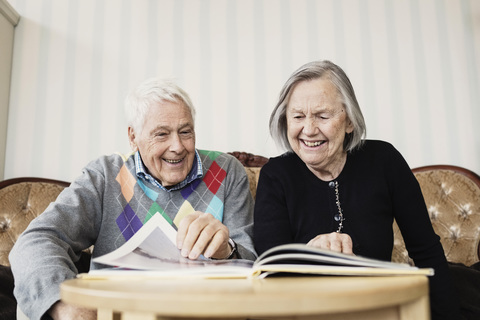 Happy senior couple reading book in living room at nursing home stock photo